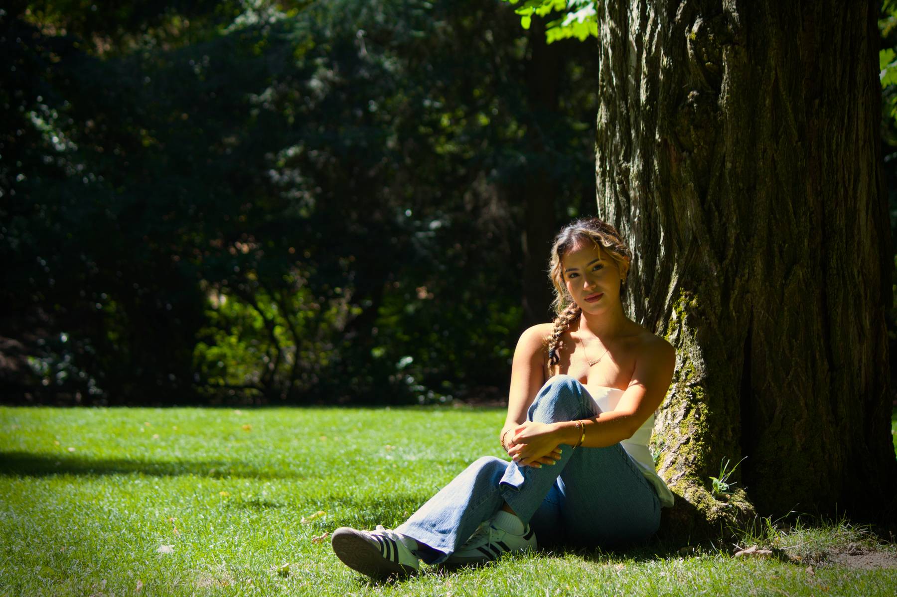 Woman sitting against a tree with her knees up