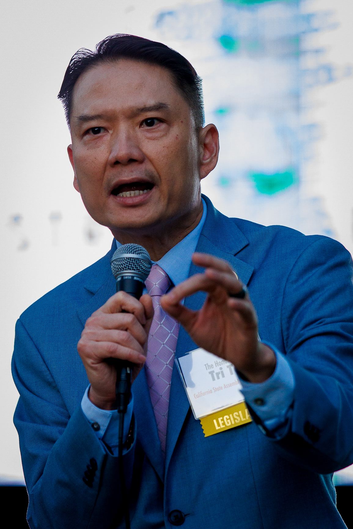 Speaker in a blue blazer addressing the crowd on stage