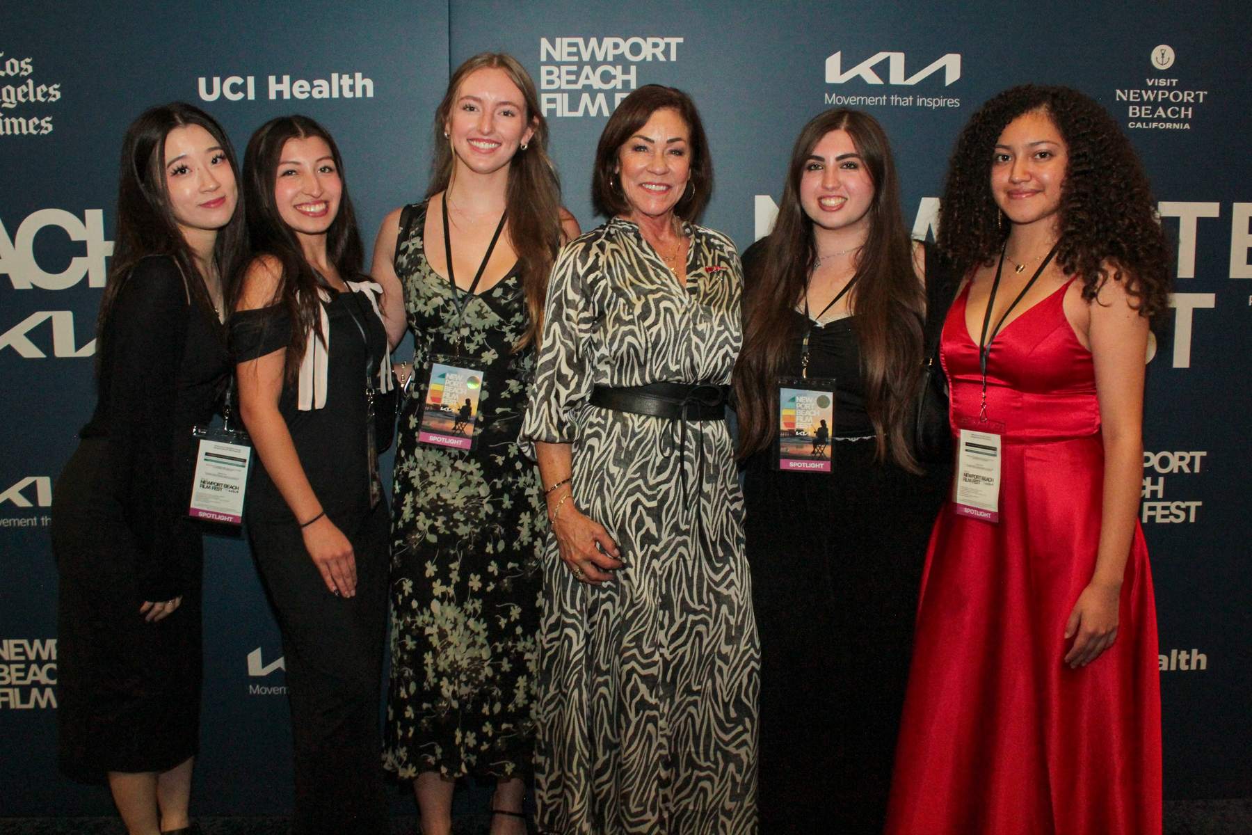 Group of women in formal wear posing on the blue carpet