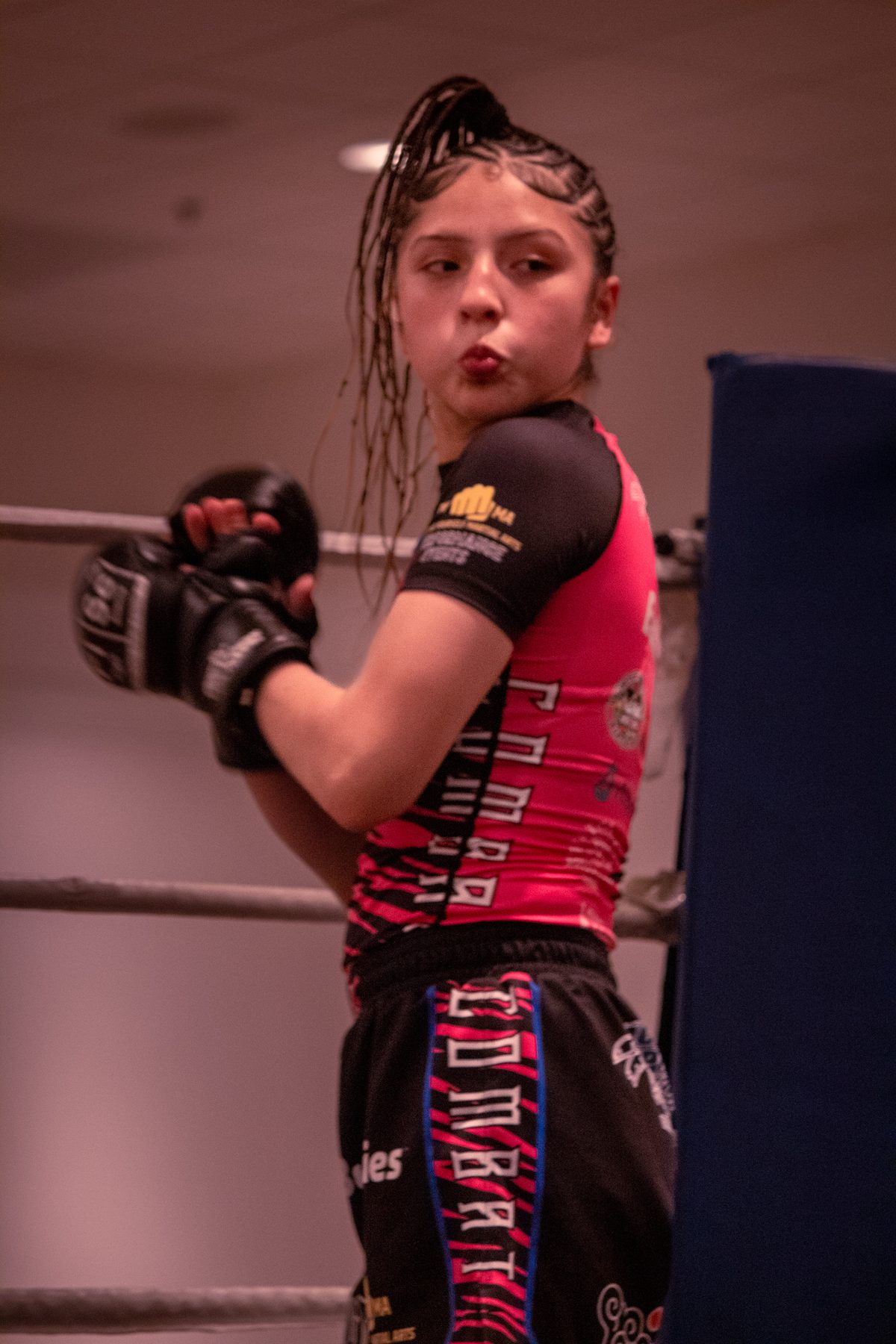 Young fighter in gloves and braids posing inside the ring