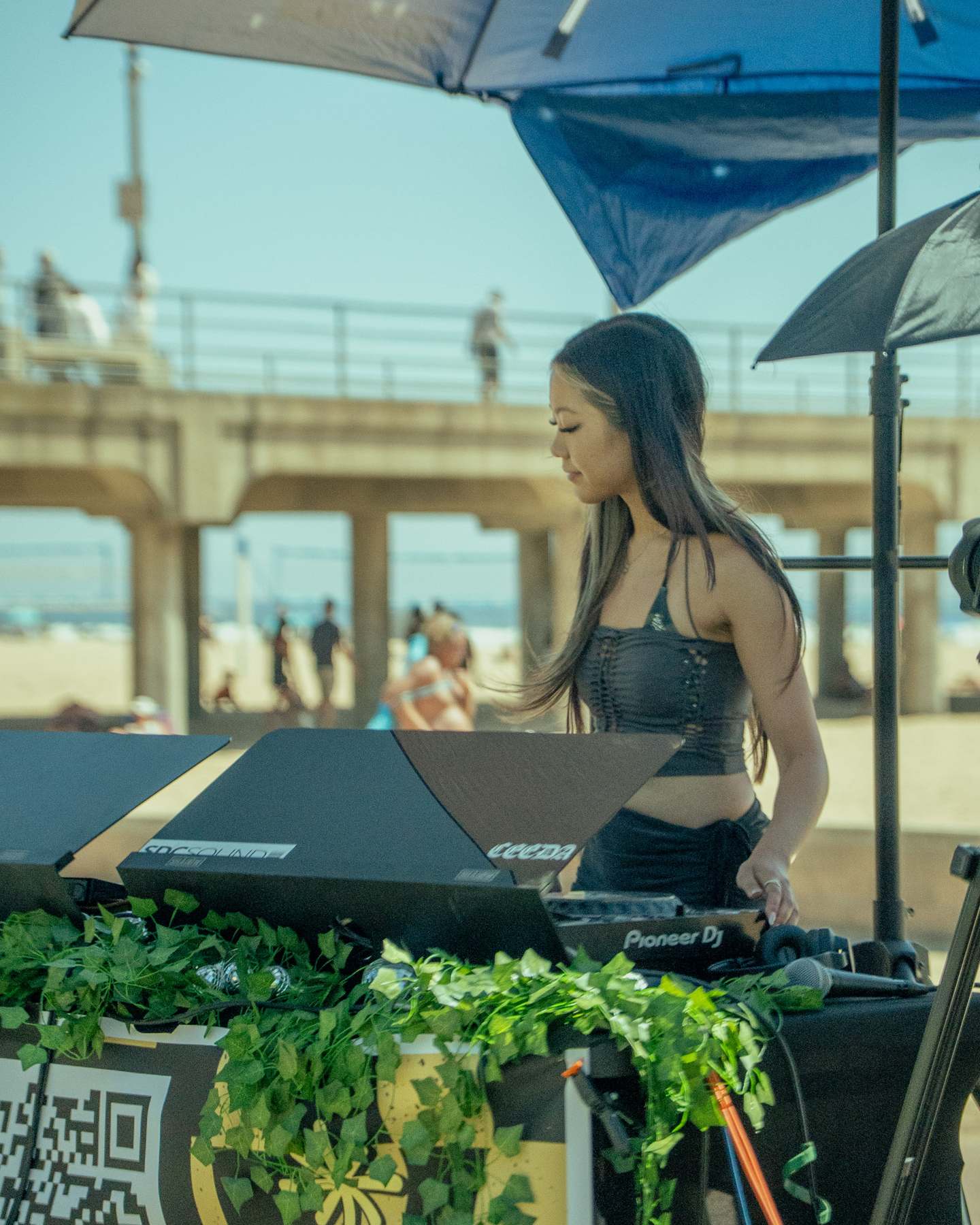 DJ in a black top at the decks with the pier in the background