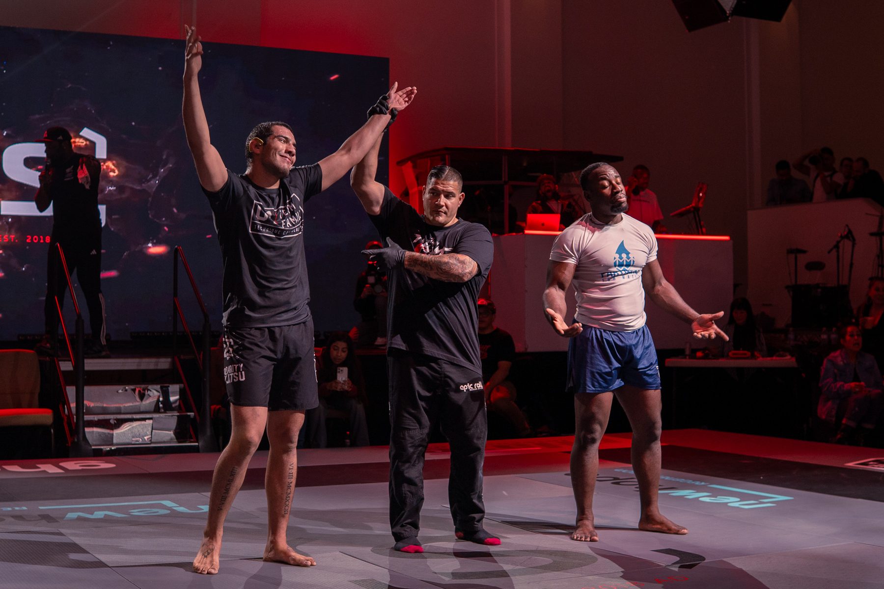 Referee raising a winner's hand at the center of the stage