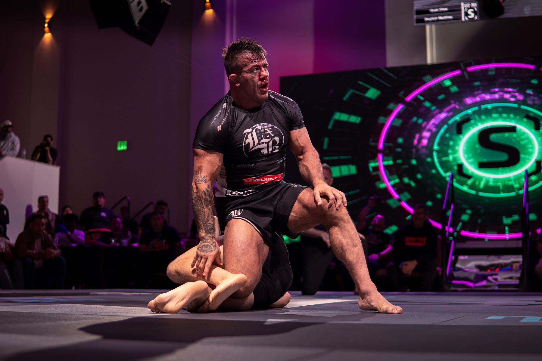 Fighter on the mat in front of the glowing S screen