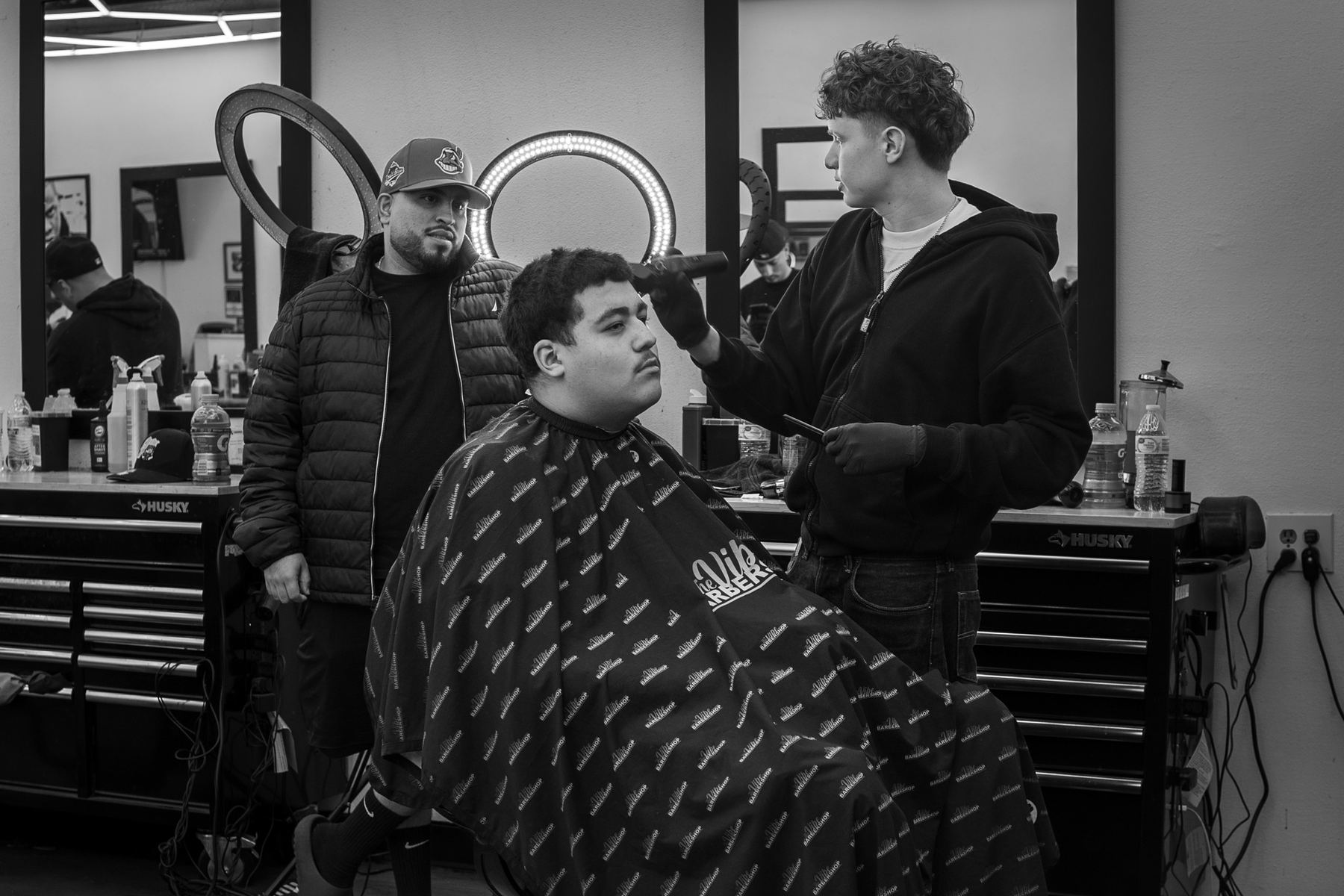 Barber working in the shop while a client waits in the chair