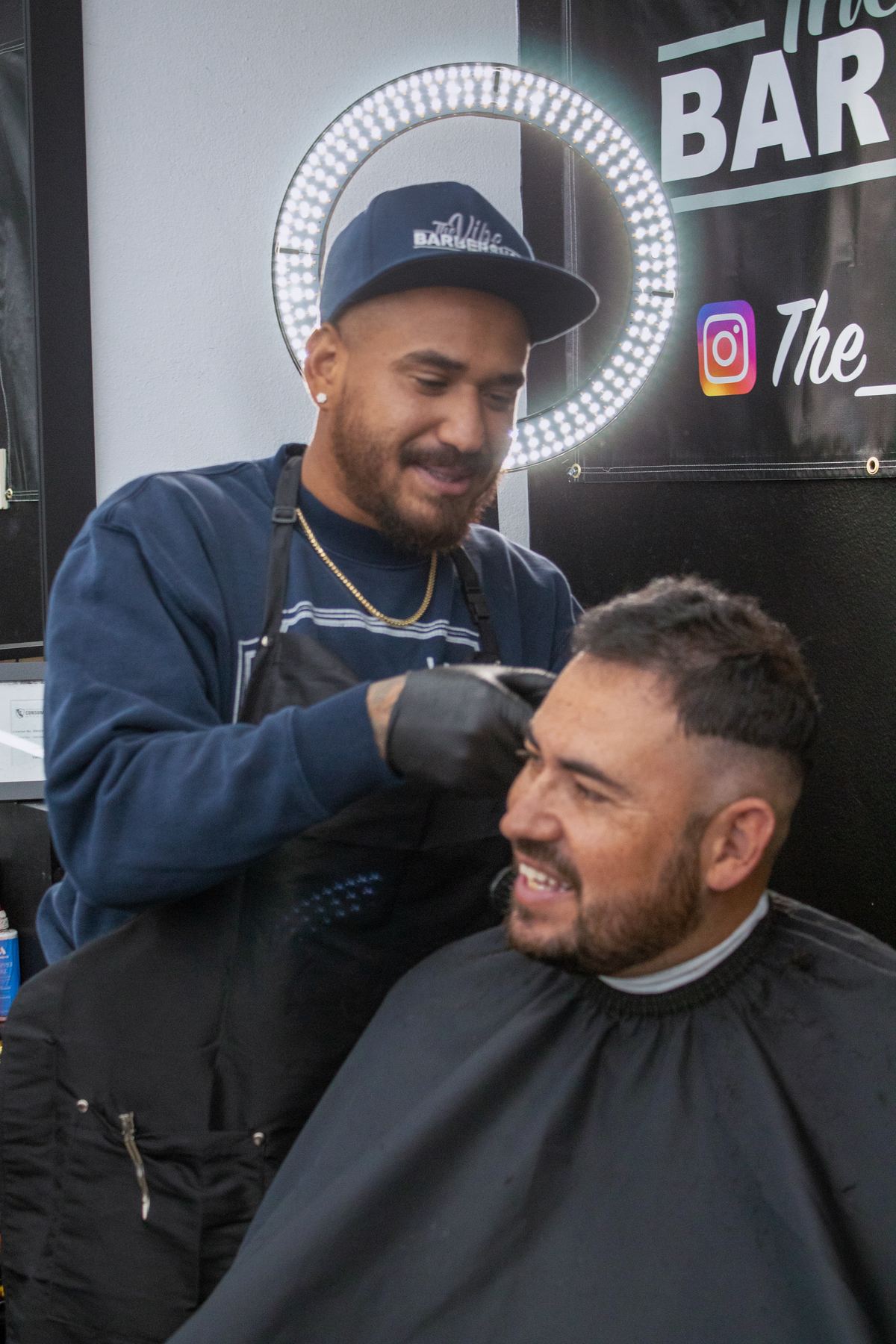 Barber giving a smiling client a haircut in front of the ring light