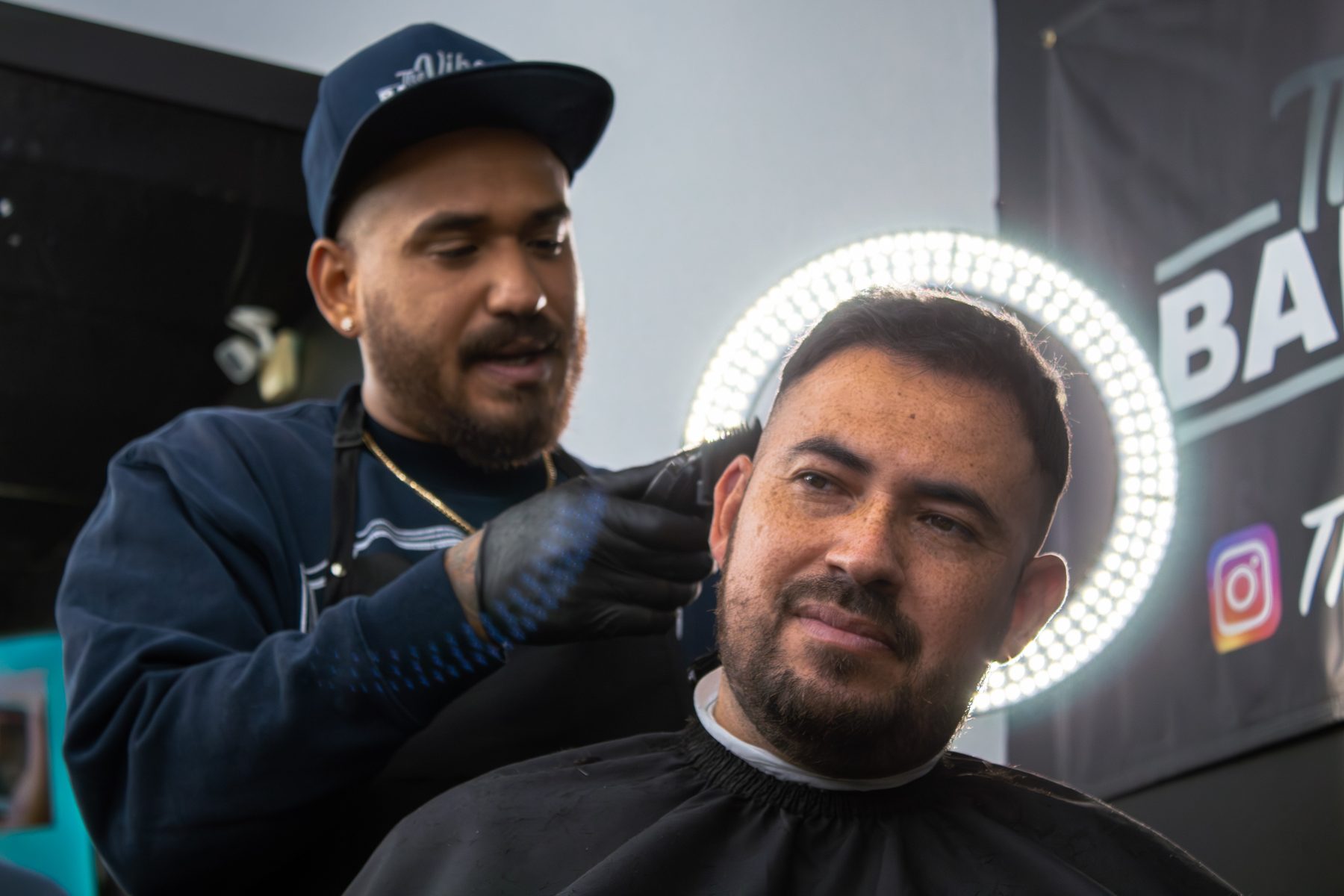 Barber and client in front of The Vibe Barbershop sign