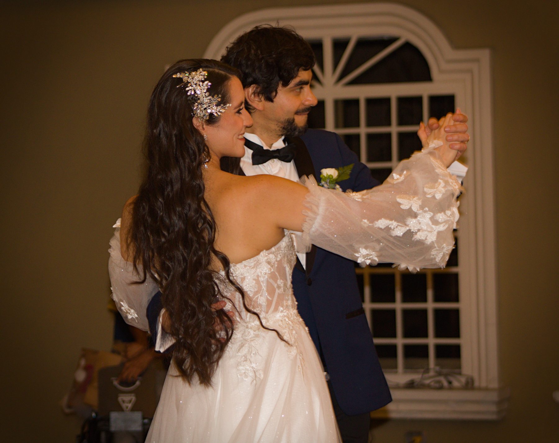 Bride and groom dancing together by an arched window