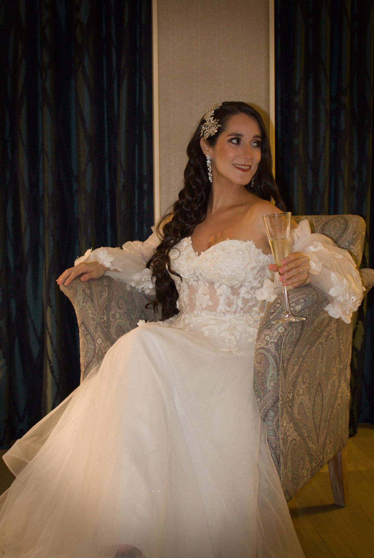 Bride seated in a wicker chair holding a champagne flute