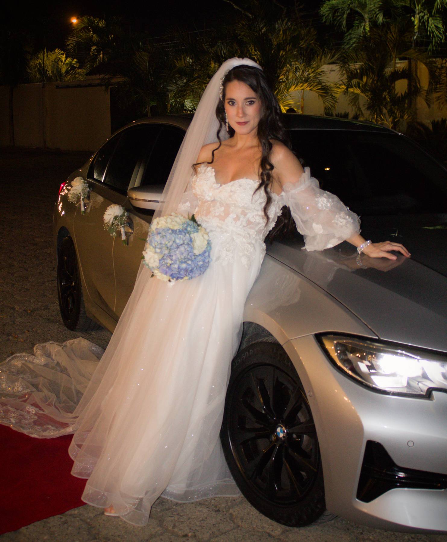 Bride standing beside a silver car at night